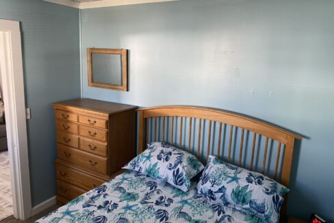 a bedroom with a bed, dresser and mirror.