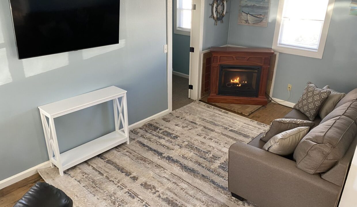 a living room with a couch, chair, television and fireplace.