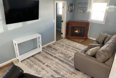 a living room with a couch, chair, television and fireplace.