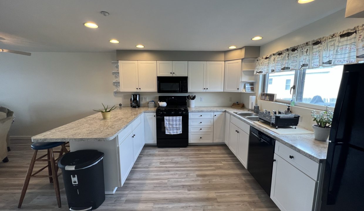 a kitchen with white cabinets and black appliances.