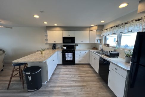 a kitchen with white cabinets and black appliances.