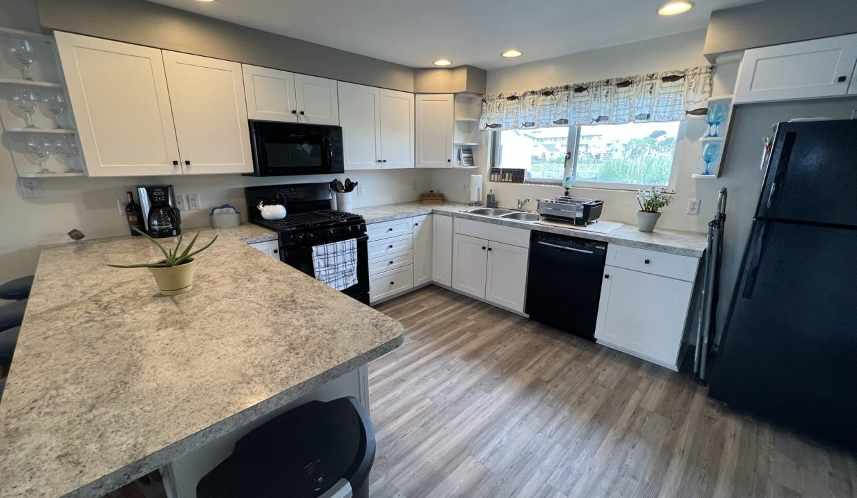 a kitchen with white cabinets and black appliances.