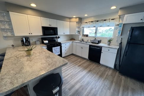 a kitchen with white cabinets and black appliances.