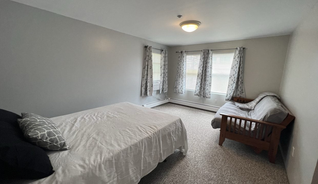 a bed room with a neatly made bed and a window.