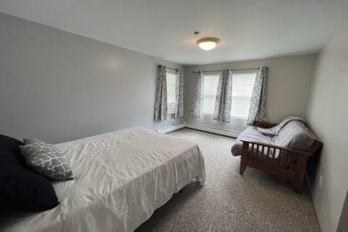 a bed room with a neatly made bed and a window.