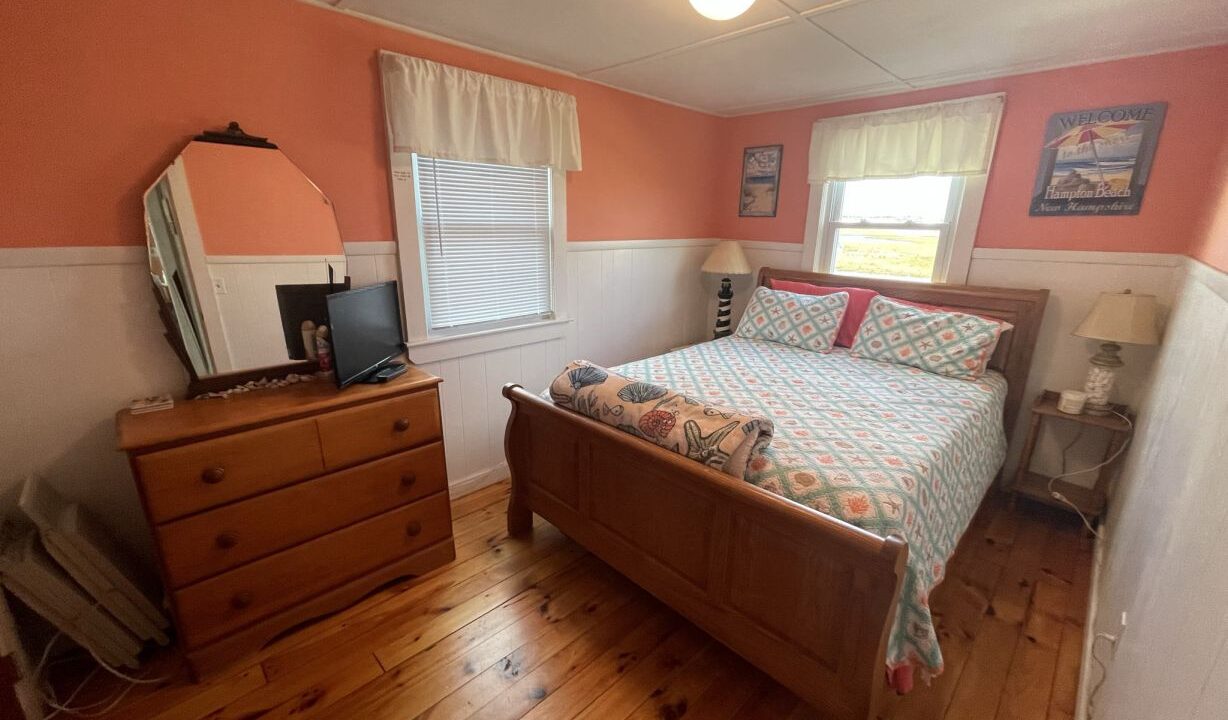 a bed room with a neatly made bed and a dresser.