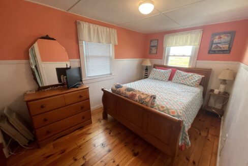 a bed room with a neatly made bed and a dresser.