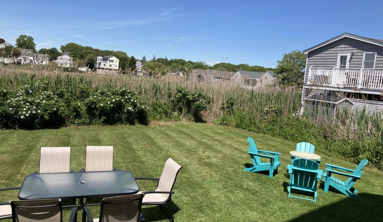 a lawn with a table and chairs and a house in the background.