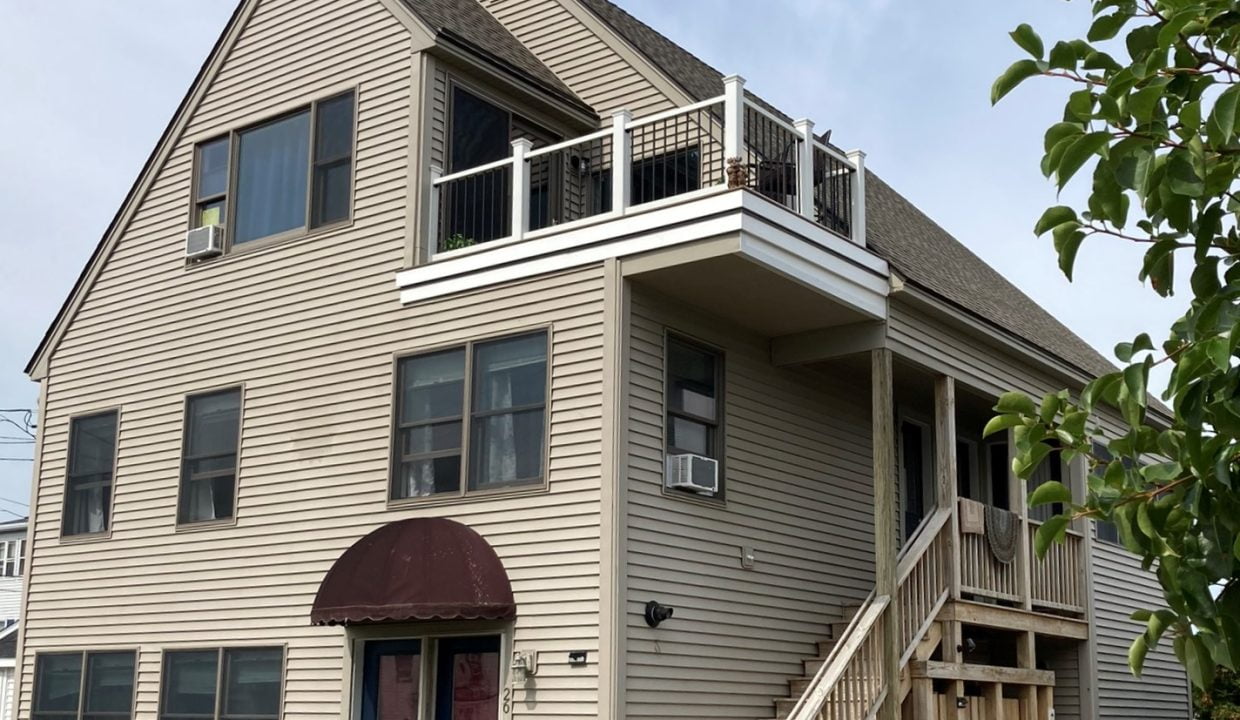 a two story house with a porch and stairs.