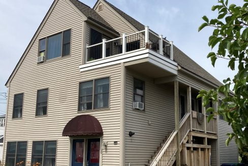 a two story house with a porch and stairs.