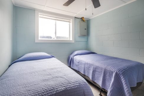 two beds in a room with a ceiling fan.