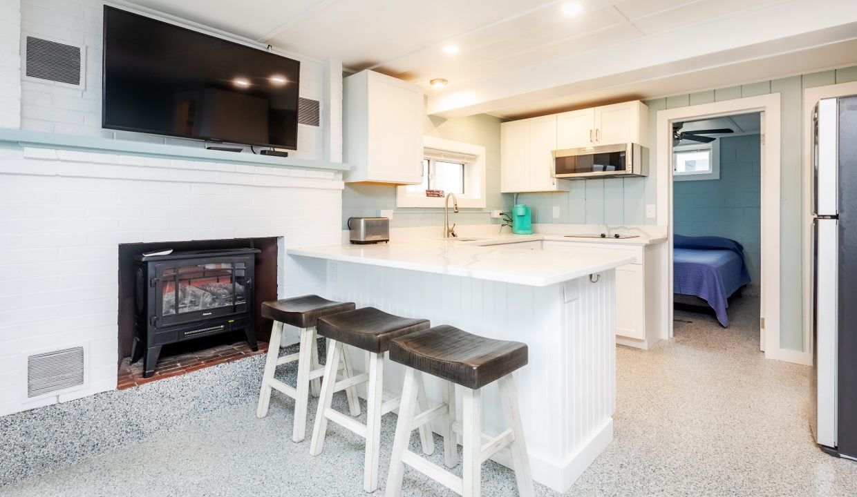 a kitchen with a tv and bar stools.