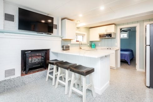 a kitchen with a tv and bar stools.