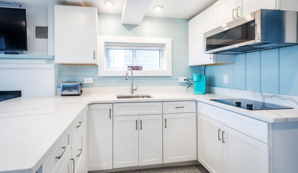a kitchen with white cabinets and blue walls.