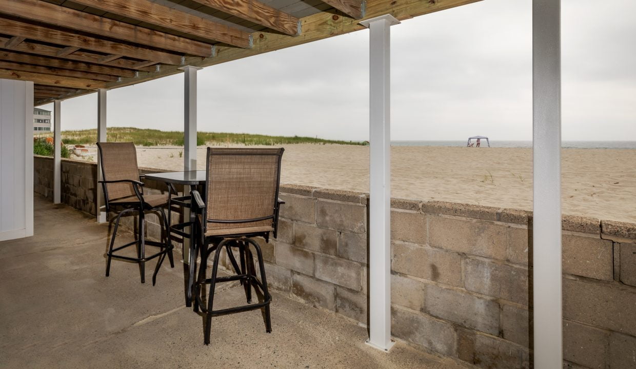 a patio with a table and chairs and a view of the beach.