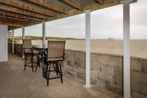 a patio with a table and chairs and a view of the beach.