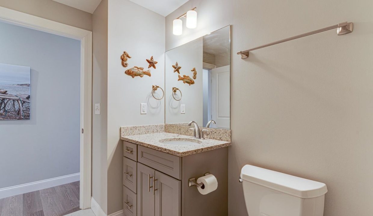 a bathroom with a sink, toilet, and mirror.