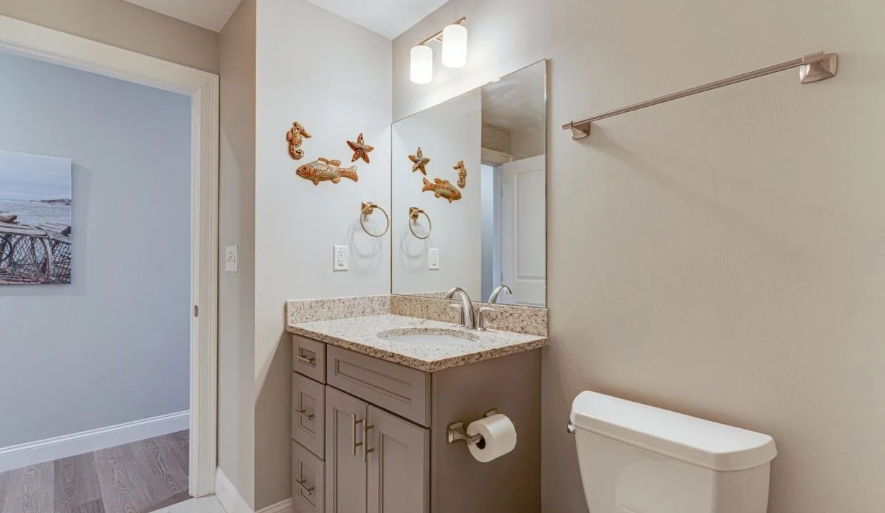 a bathroom with a sink, toilet, and mirror.