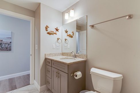 a bathroom with a sink, toilet, and mirror.