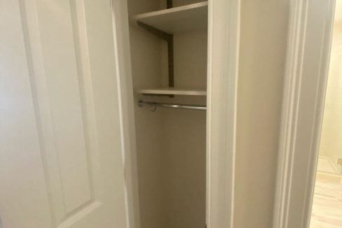 an empty closet with a door open to reveal a closet.