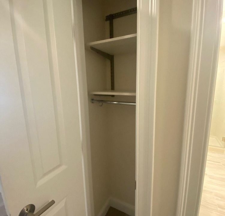 an empty closet with a door open to reveal a closet.