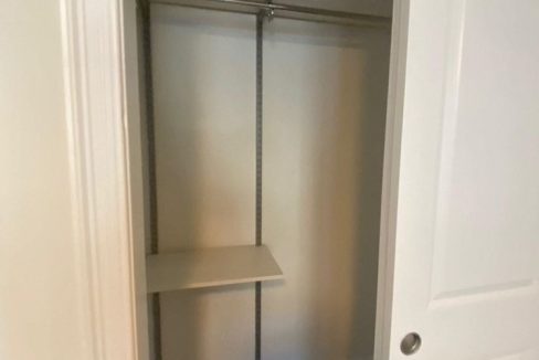 an empty closet with a shelf and a door.