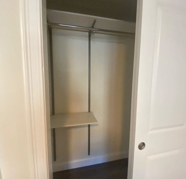 an empty closet with a shelf and a door.