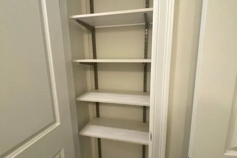 a walk in closet with shelves and a door.