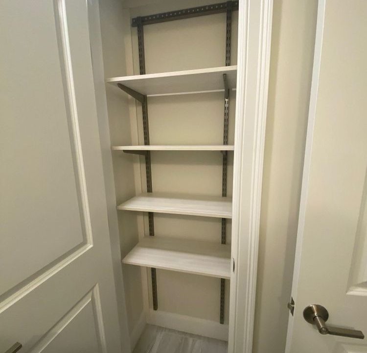 a walk in closet with shelves and a door.