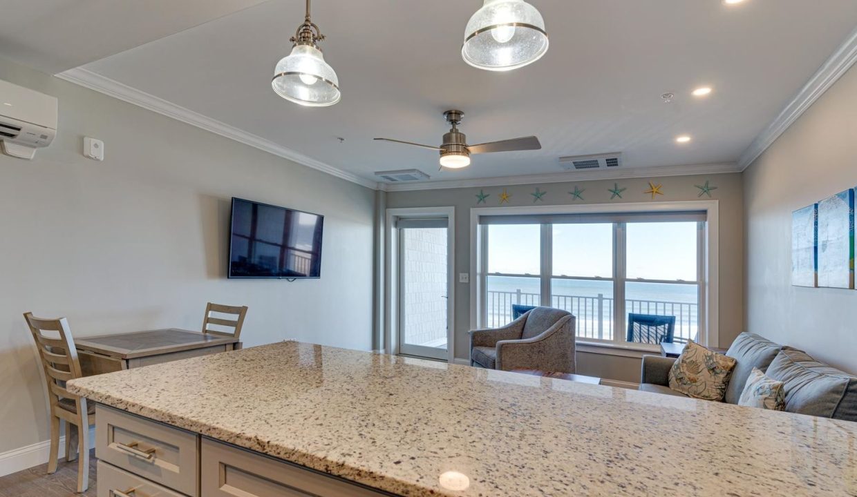 a kitchen with a large counter top next to a living room.