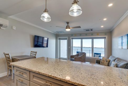 a kitchen with a large counter top next to a living room.