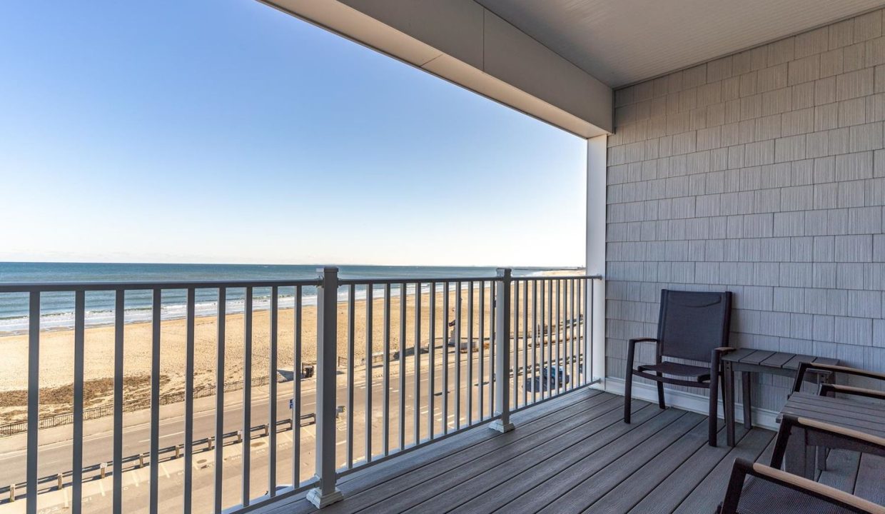 a balcony with chairs and a view of the beach.