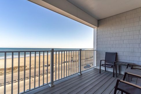 a balcony with chairs and a view of the beach.