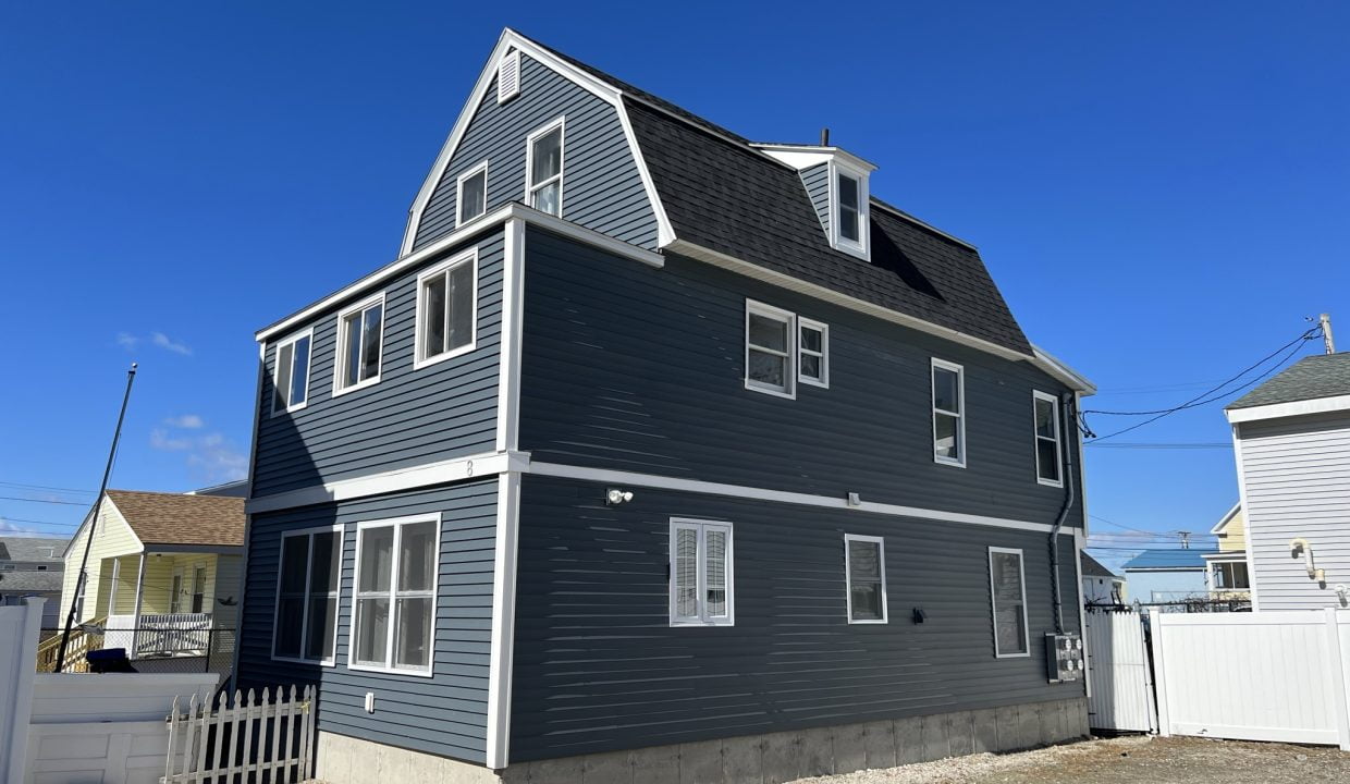 a large gray house with a white fence around it.