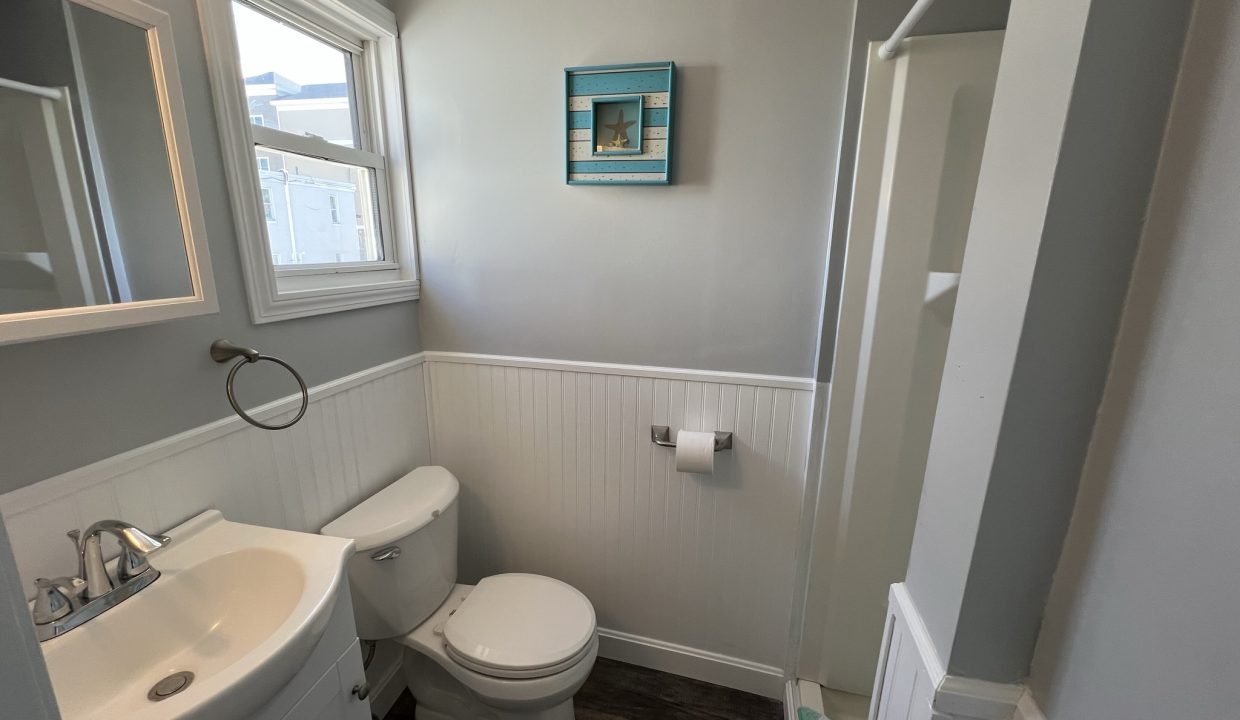 a bathroom with a toilet, sink, and mirror.