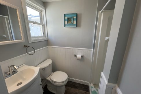 a bathroom with a toilet, sink, and mirror.
