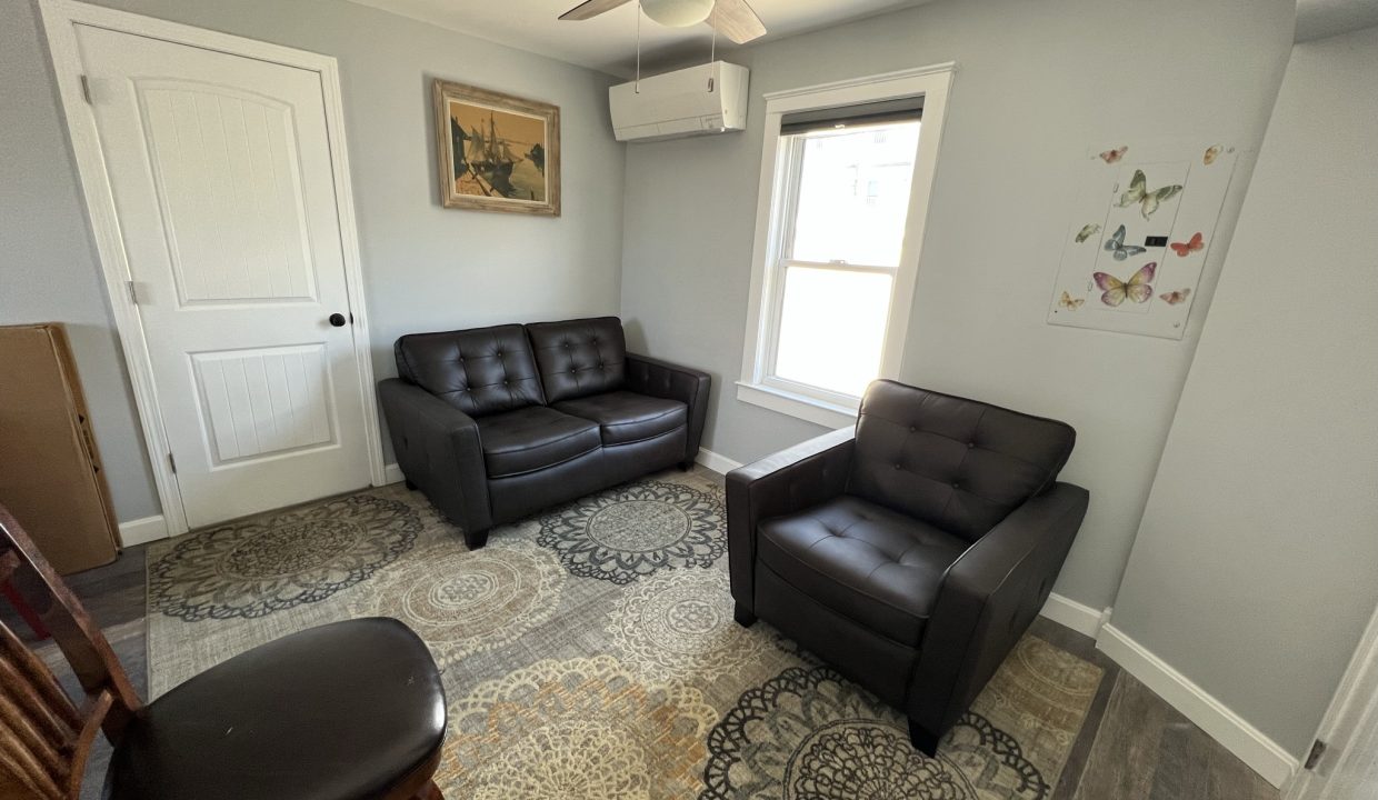 a living room with two leather chairs and a rug.