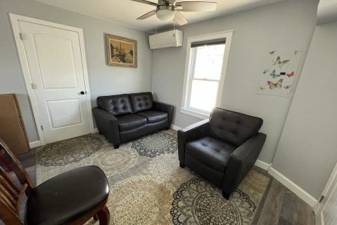 a living room with two leather chairs and a rug.