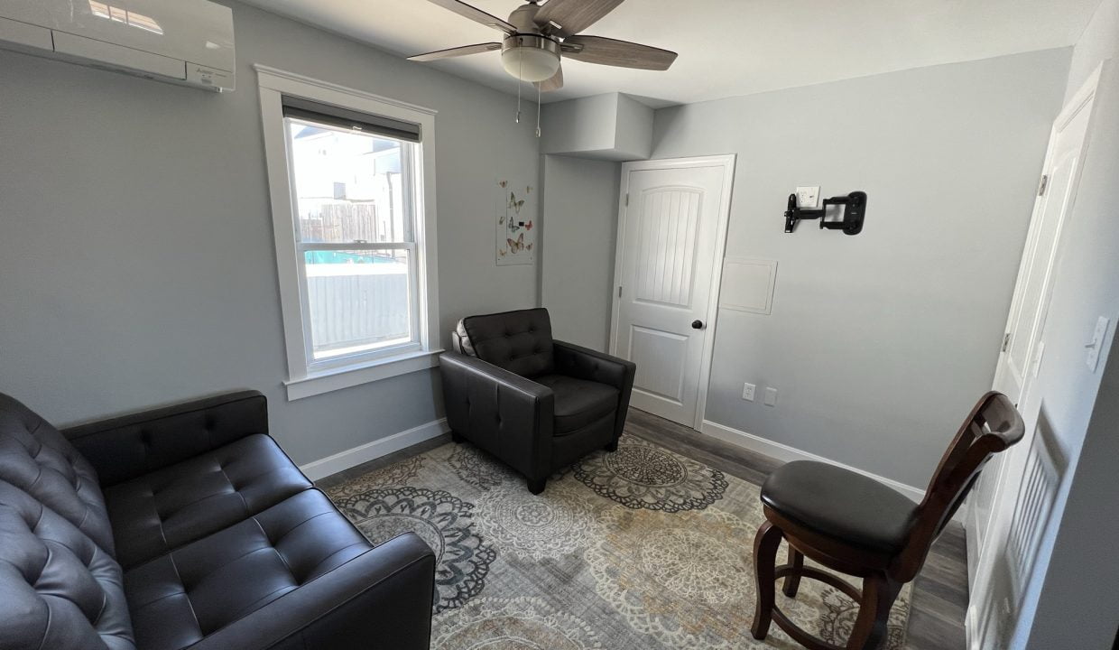 a living room with two black chairs and a rug.