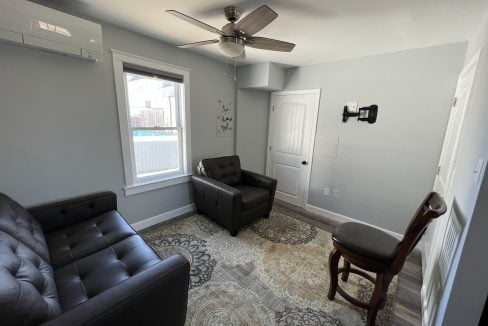 a living room with two black chairs and a rug.