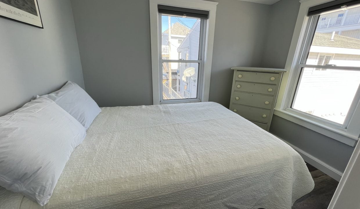 a bedroom with a bed and two windows.