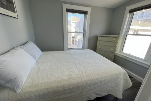 a bedroom with a bed and two windows.