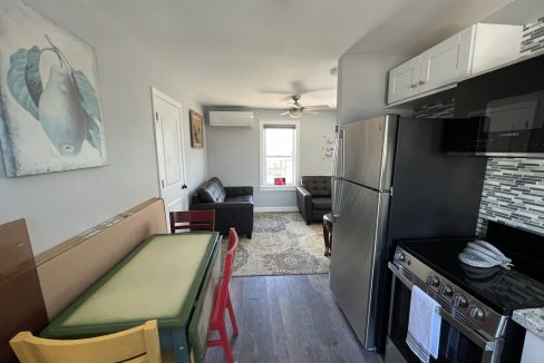 a kitchen with a refrigerator, stove, table and chairs.