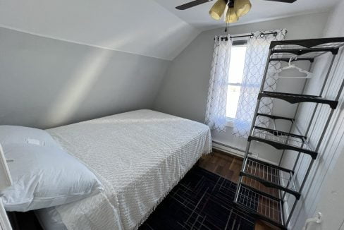 a bedroom with a bed and a ceiling fan.