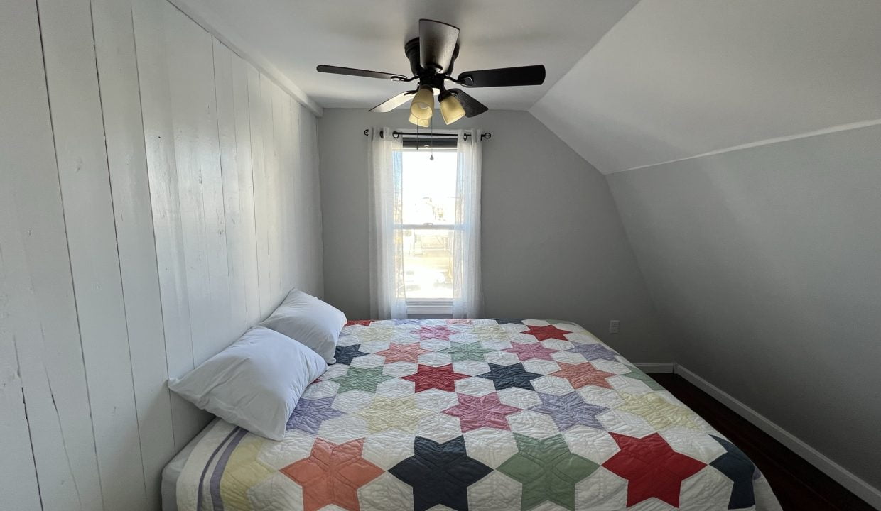 a bedroom with a bed and a ceiling fan.