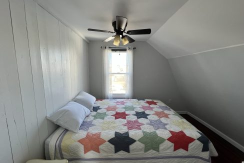 a bedroom with a bed and a ceiling fan.