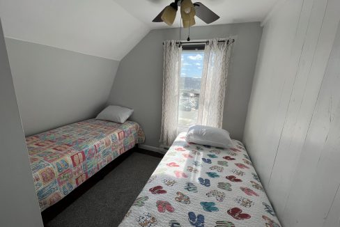 a bedroom with two beds and a ceiling fan.
