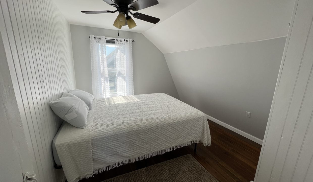 a bedroom with a bed and a ceiling fan.