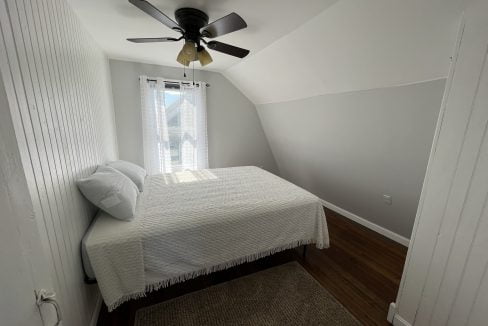 a bedroom with a bed and a ceiling fan.