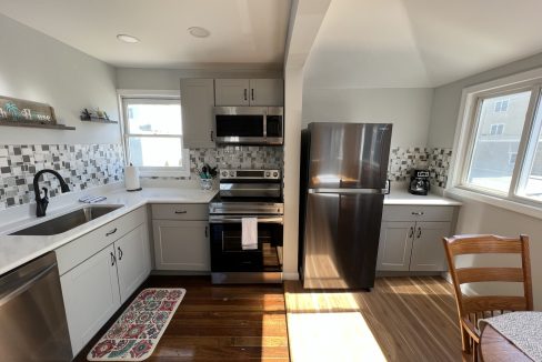 a kitchen with stainless steel appliances and a wooden floor.